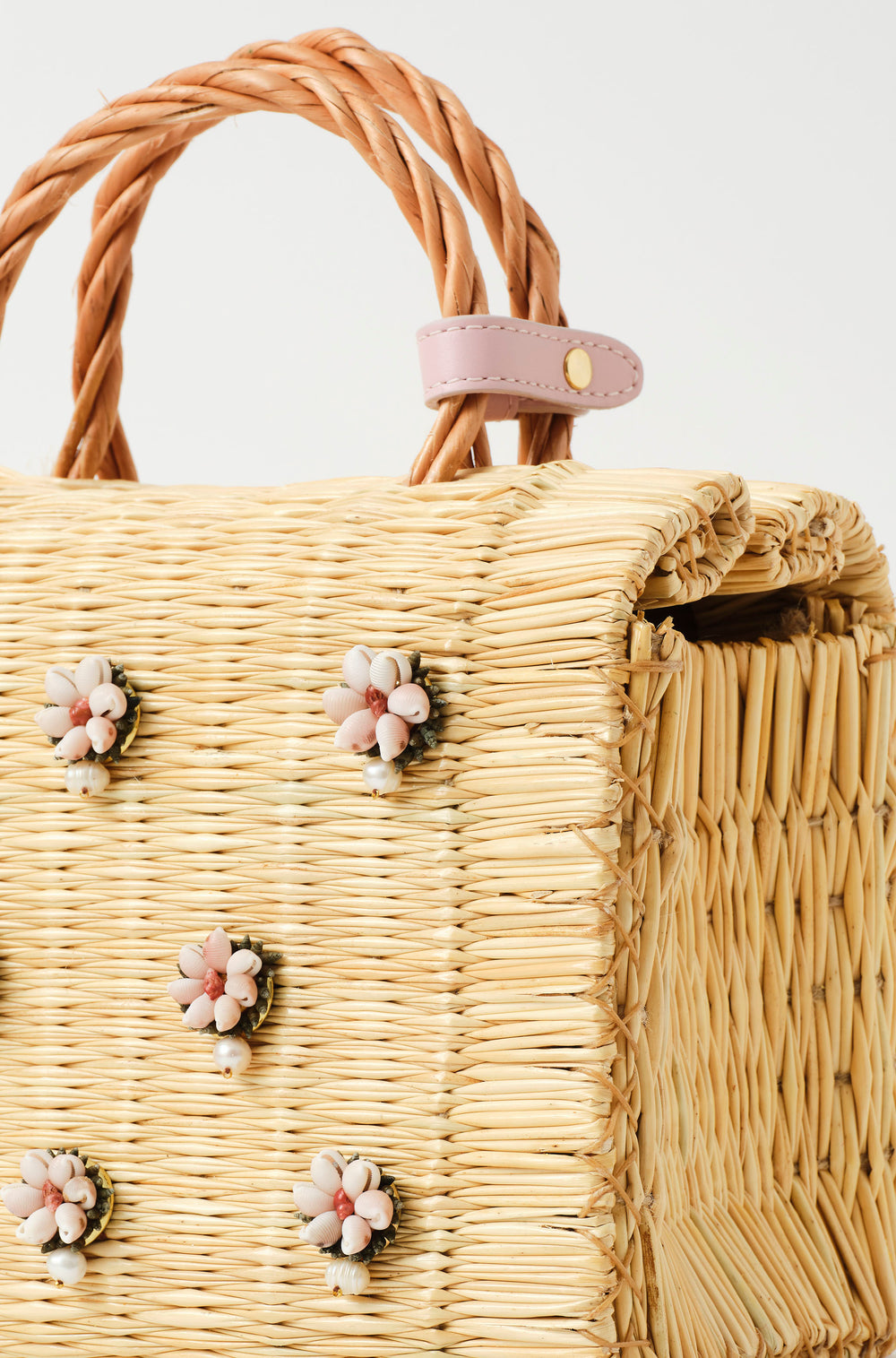 Wicker handbag with braided handle, light pink strap, and pastel floral decorations with pearl from the atlantic and leather in blush pink