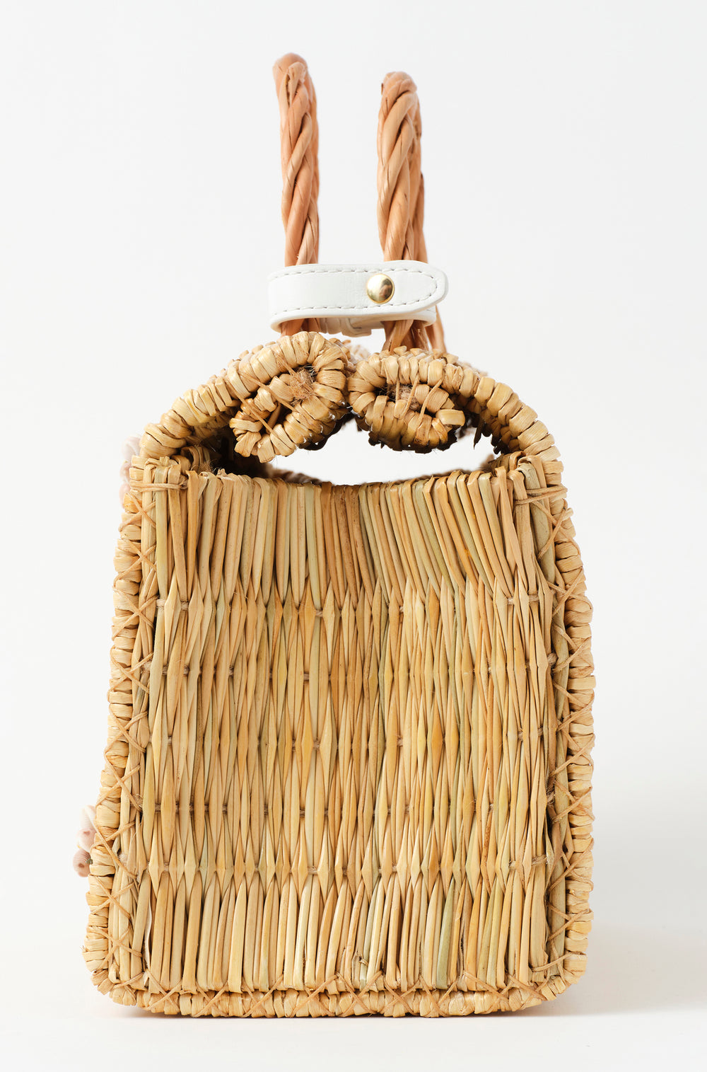Shella Medium White basket bag by Heimat Atlantica, handwoven in Portugal from reed and finished in Spain with an Atlantic shell charm. Side detail.