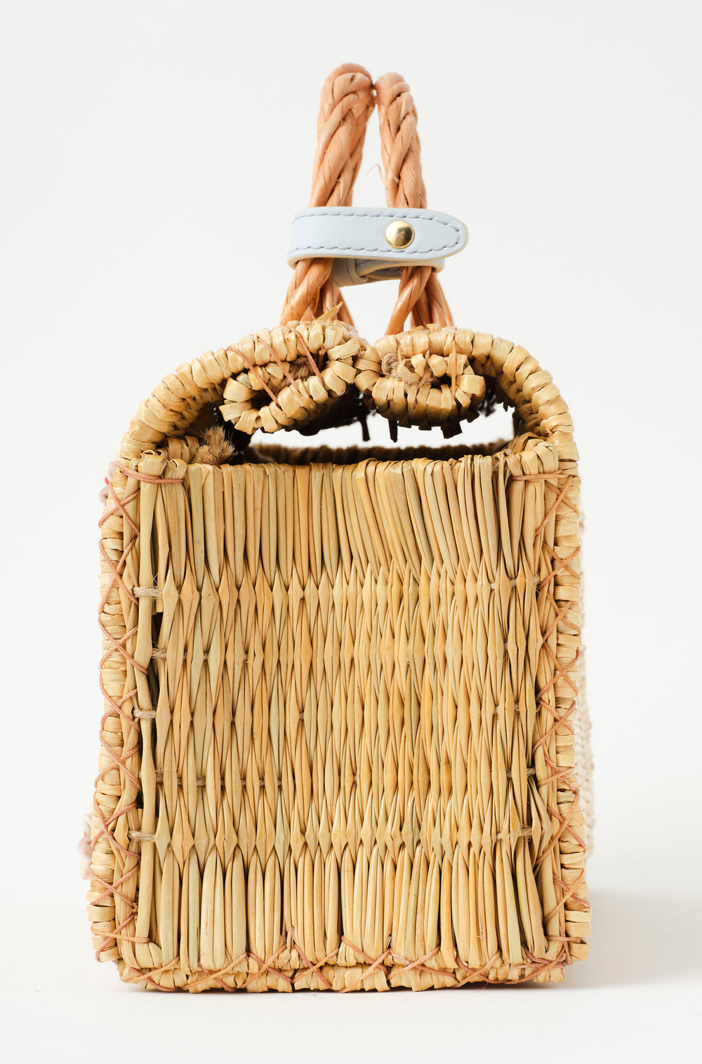 Shella basket bag by Heimat Atlantica photographed on the Atlantic coast between Spain and Portugal, celebrating shell craft, handmade tradition, and contemporary design with the feet in gold lateral detail. 
