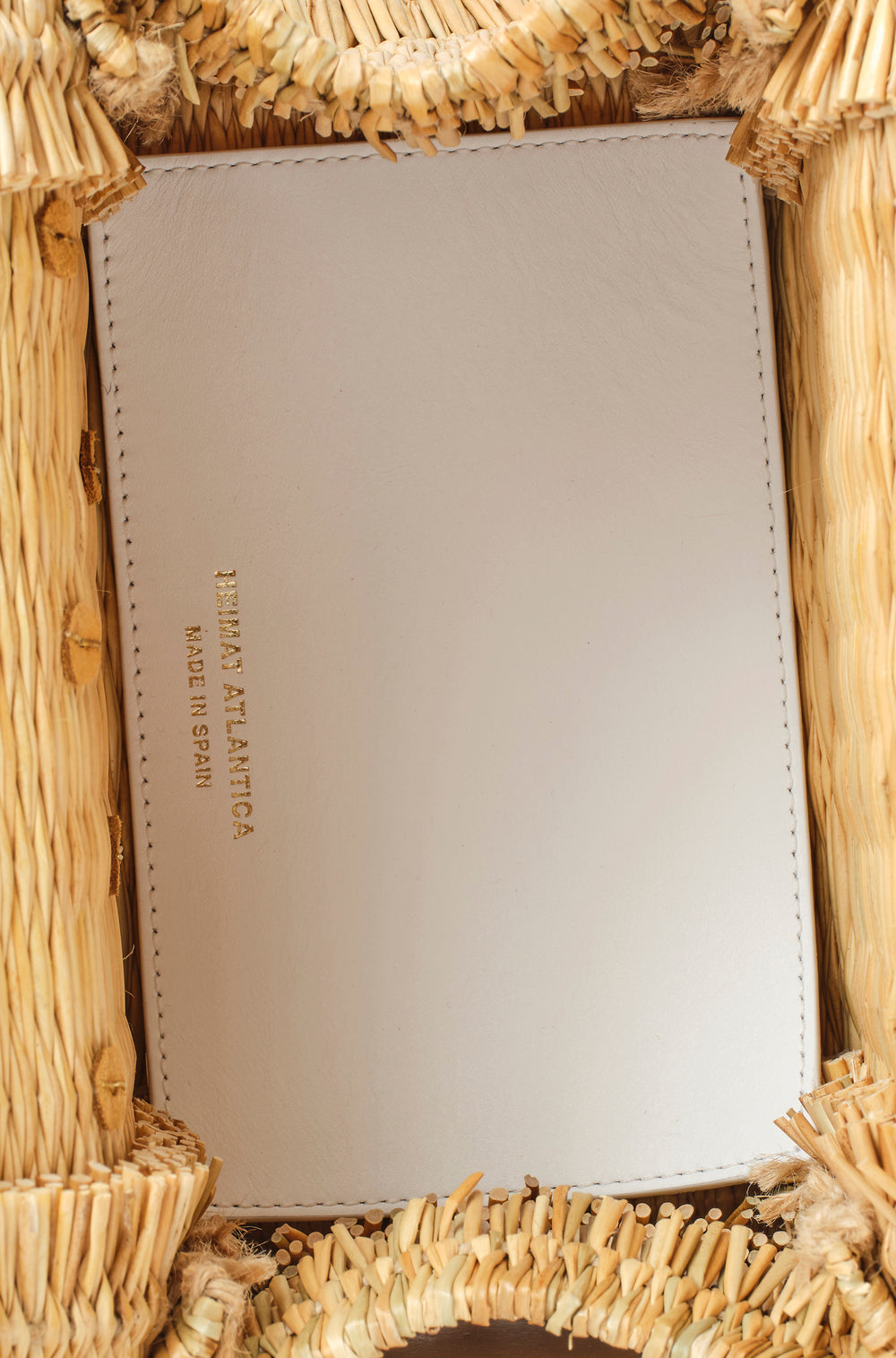 Shella Medium White basket bag by Heimat Atlantica, handwoven in Portugal from reed and finished in Spain with an Atlantic shell charm. Bag inside detail with leather in white and branding.