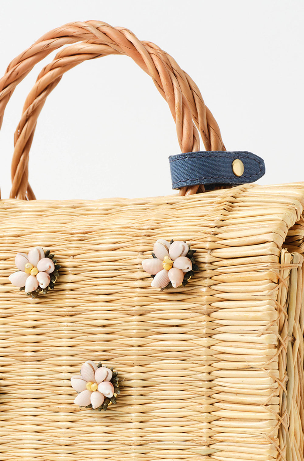 Shella Denim Classic basket bag by Heimat Atlantica, woven in Portugal from reed and finished in Spain with an Atlantic shell charm. Closure detail. 