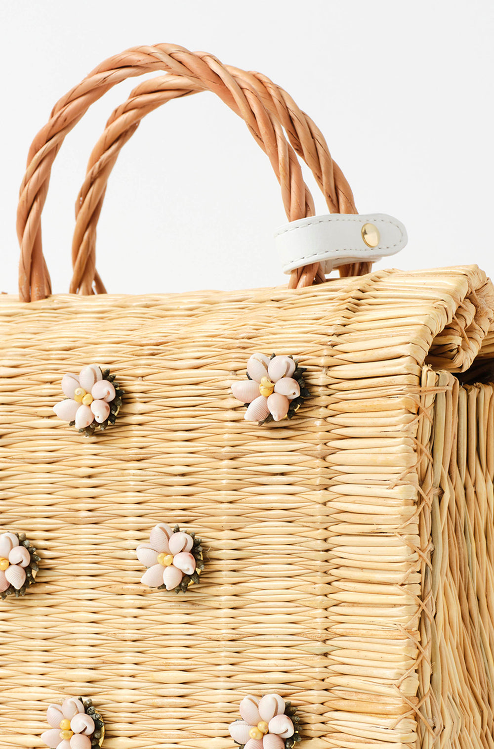 Model holding the Shella Medium White bag and wearing Lares earrings by Heimat Atlantica, standing by the Atlantic shore. With closure detail in white. 