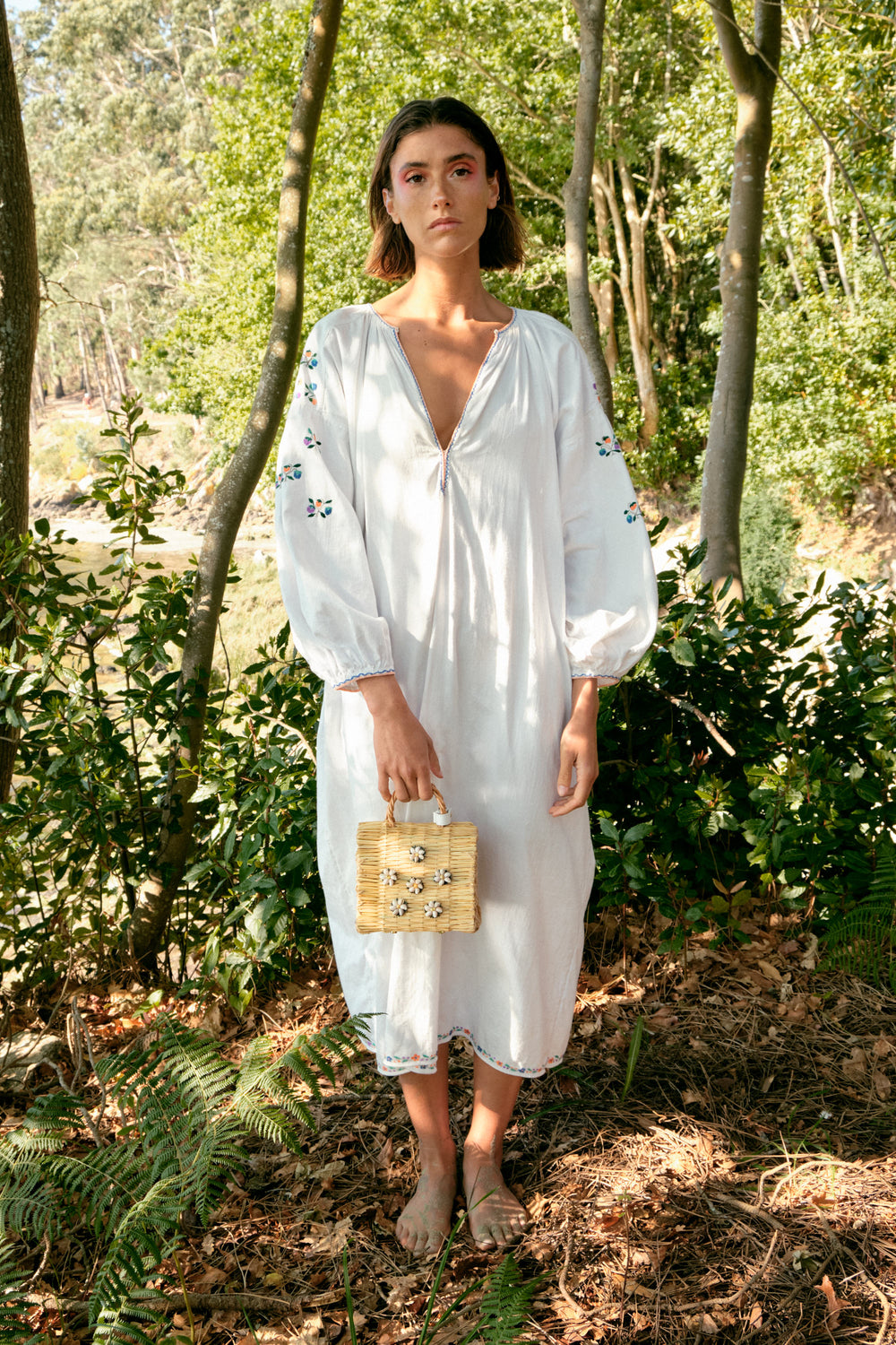 Shella Mini White basket bag by Heimat Atlantica, handwoven in Portugal from natural reed and finished in Spain with an Atlantic shell details. In model in the Atlantic nature coast. 